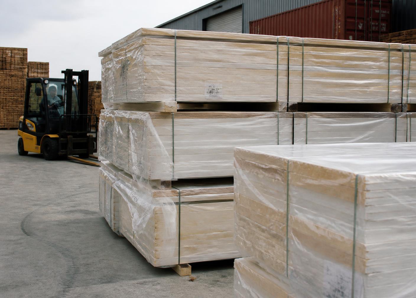 Flat-packed timber panels strapped and wrapped in a yard